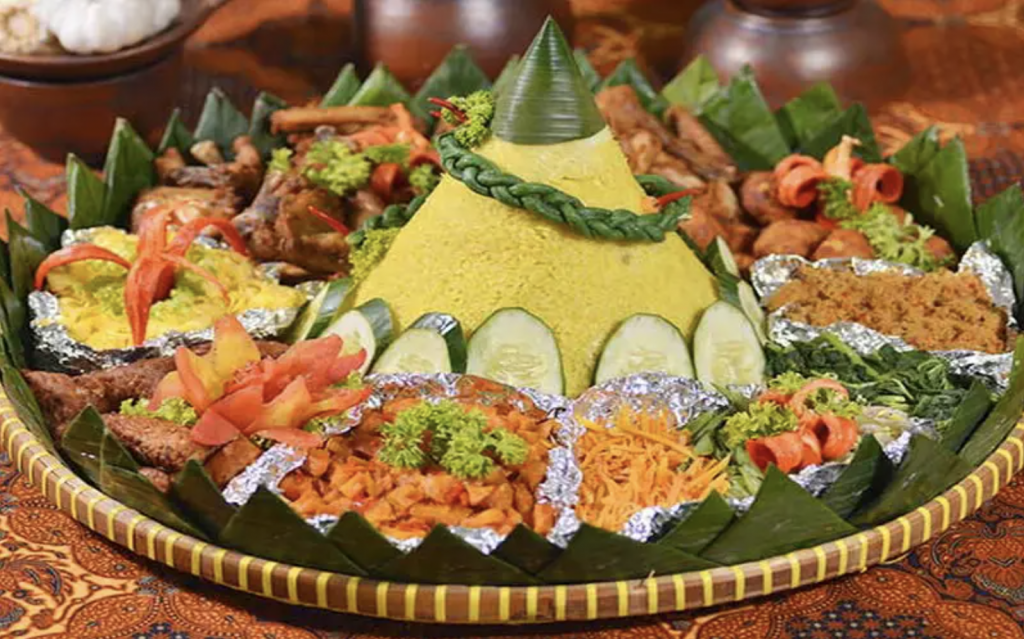 Tumpeng, a cone-shaped serving of yellow rice accompanied by assorted side dishes) is synonymous with joyful celebrations. (Source: https://beyondarie.com/sejarah-tumpeng-dari-ritual-keagamaan-ke-perayaan/)